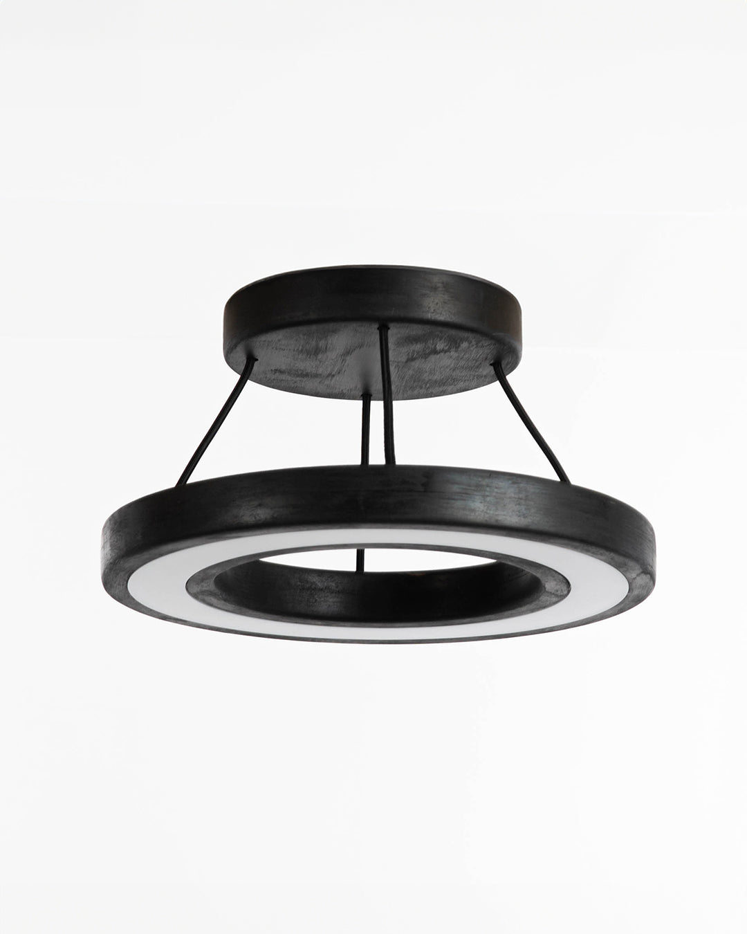Lámpara de techo Runden en madera de pino con terminación en negro. Consta de un soporte circular con cuatro cables de tela que soportan la pantalla de iluminación en base a luces LEDs.