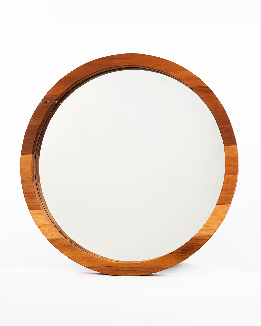 Espejo circular de dos capas en madera de raulí, situado sobre un fondo blanco, que resalta su estética minimalista y natural. 