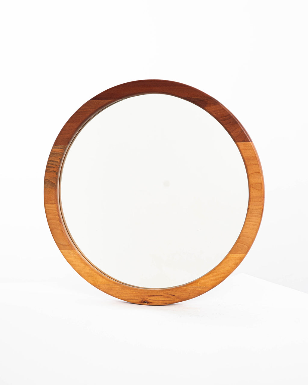 Espejo circular de una capa en madera de raulí, situado sobre un fondo blanco, que resalta su estética minimalista y natural.