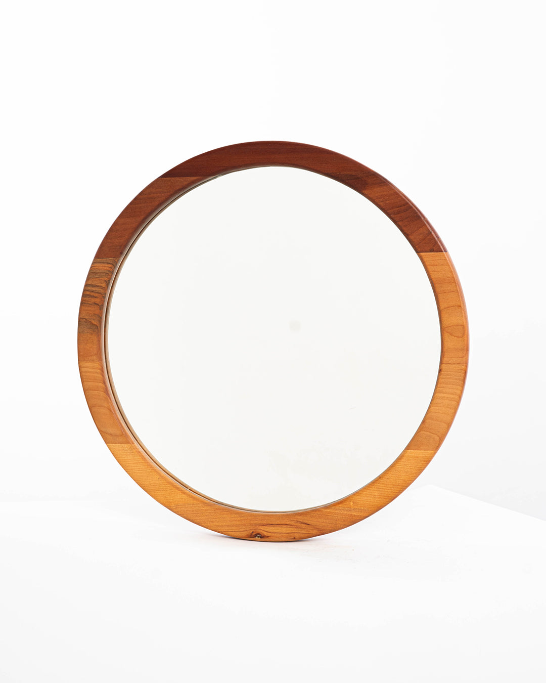 Espejo circular de una capa en madera de raulí, situado sobre un fondo blanco, que resalta su estética minimalista y natural.
