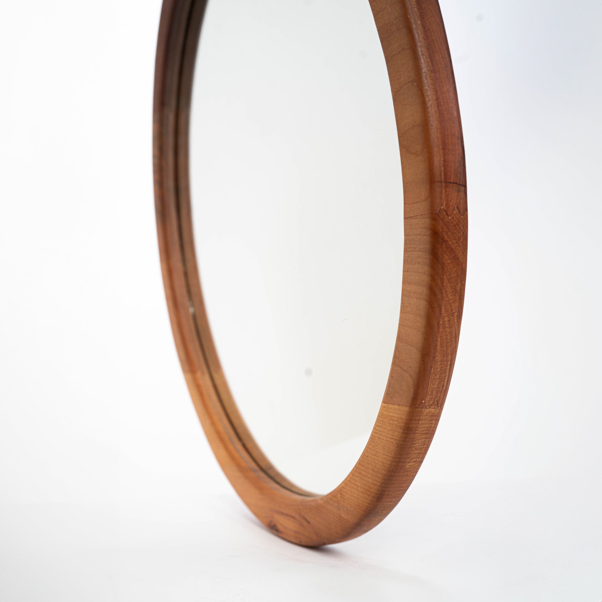 Espejo circular de una capa en madera de raulí, toma desde el costado mostrando el espesor de este espejo. Ideal para decorar cualquier espacio de tu hogar.