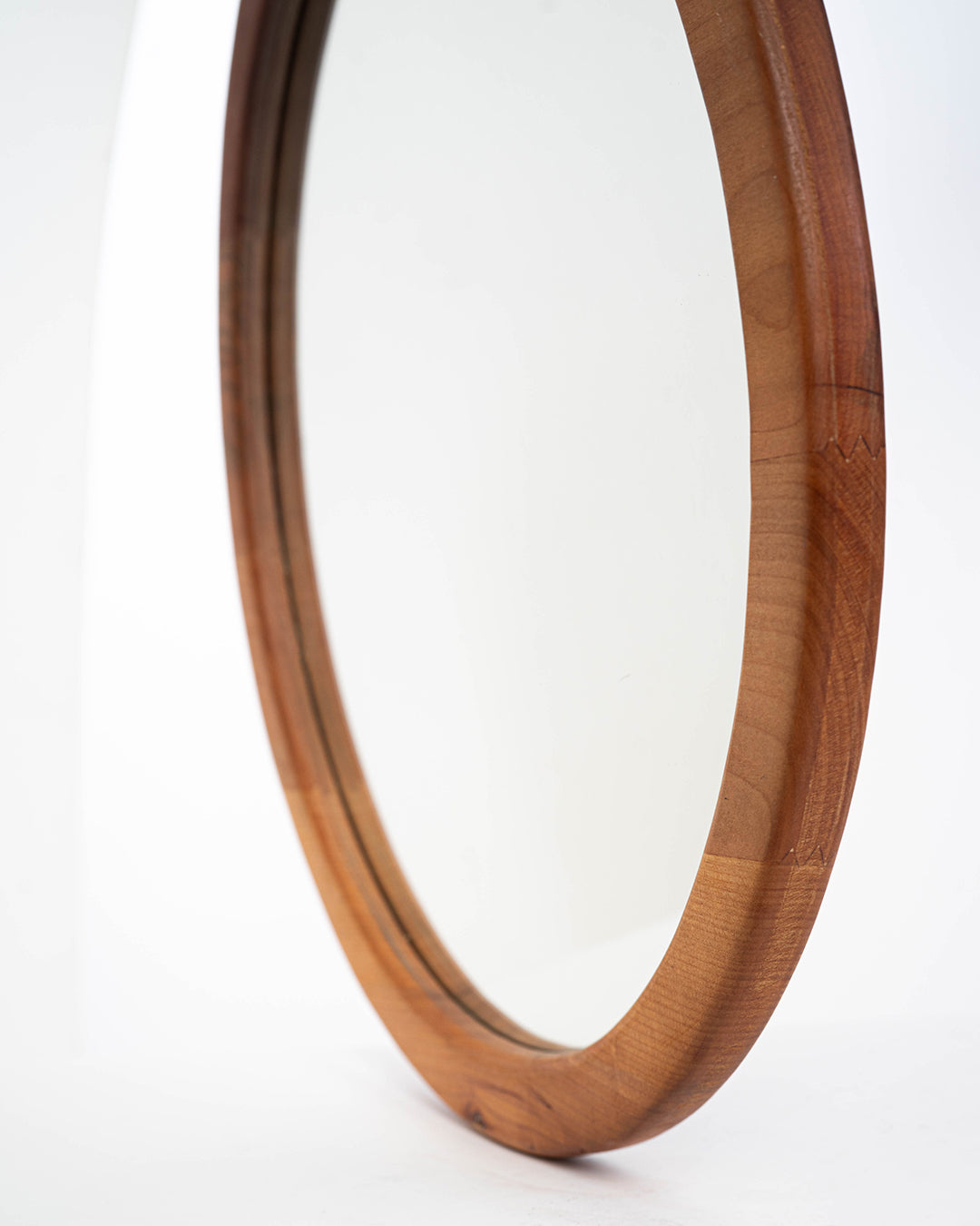 Espejo circular de una capa en madera de raulí, toma desde el costado mostrando el espesor de este espejo. Ideal para decorar cualquier espacio de tu hogar.