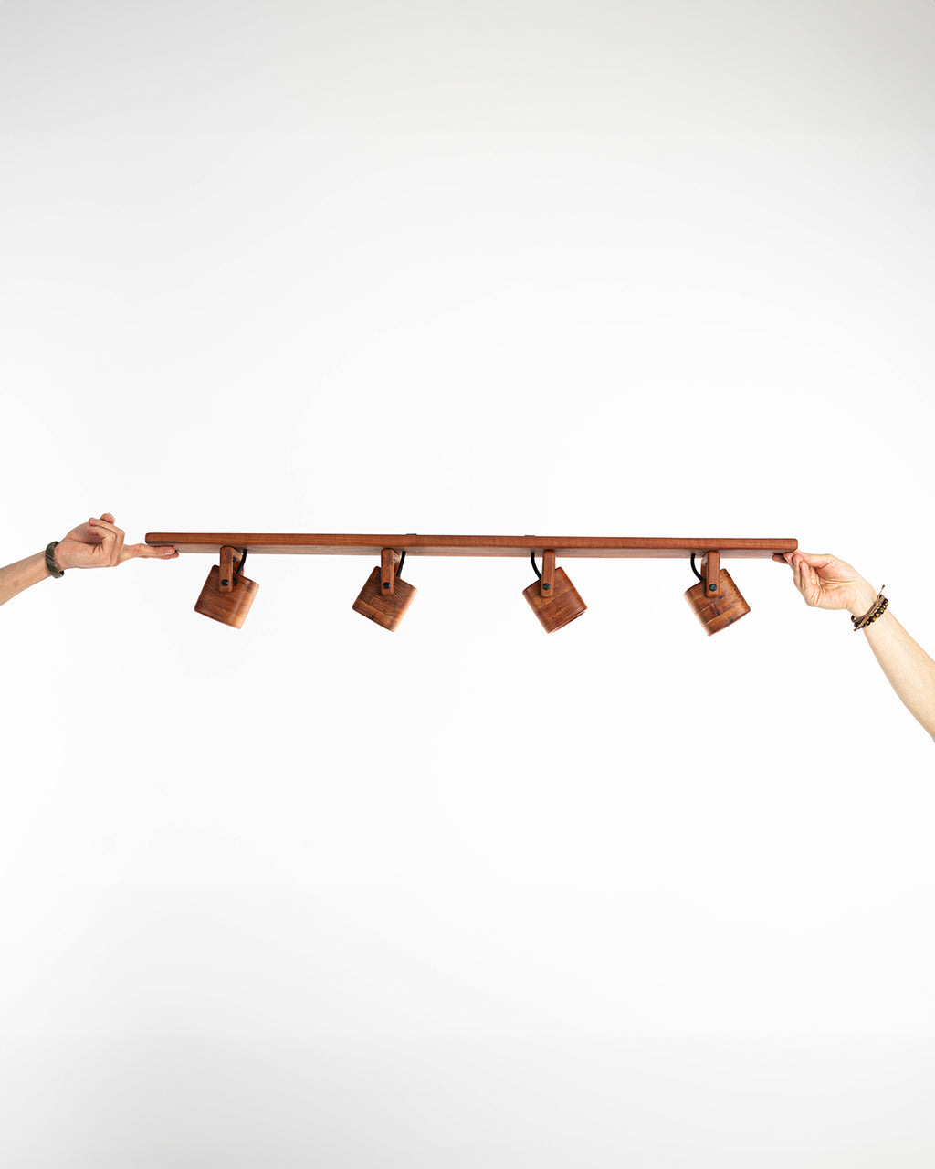 Imagen en primer plano del set de focos en madera de raulí sostenido por dos manos para dar proporción del tamaño