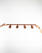 Imagen en primer plano del set de focos en madera de raulí sostenido por dos manos para dar proporción del tamaño