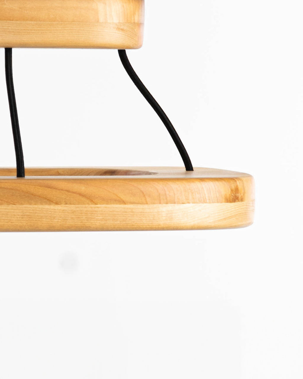  Imagen lateral de lámpara de techo quadrat en madera de lenga. Se aprecia la proporción entre su base y su pantalla de iluminación. Además se puede ver la estética que le aportan los cables de tela negros en la unión de ambas piezas.