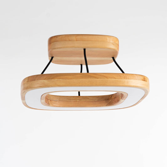 Lámpara de techo Quadrat  en madera de lenga. Consta de un soporte cuadrado con cuatro cables de tela que soportan la pantalla de iluminación en base a luces LEDs